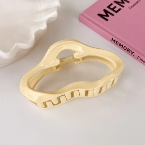 Detailed view of the wavy cream yellow acrylic hair claw clip with glossy finish
