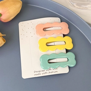 Trois barrettes à cheveux ondulées aux couleurs pastel sur carte en rose jaune vert
