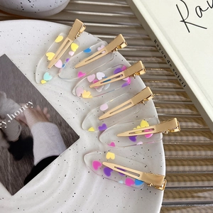 Set of six colorful transparent acrylic heart hair clips on a decorative white porcelain tray