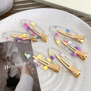 Close-up of six colorful transparent acrylic hair clips with embedded heart patterns