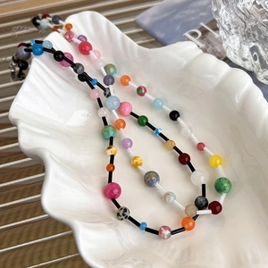 Close-up of vibrant colorful beaded necklace displayed in a white seashell porcelain dish