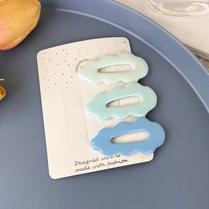 Vue détaillée de trois barrettes à cheveux en résine en forme de nuage bleu et vert