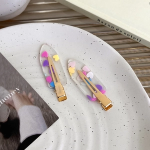 Detail of two transparent acrylic heart hair clips with colorful accents in a decor tray