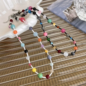 Detail of colorful dopamine crystal beaded necklaces on a white shell tray
