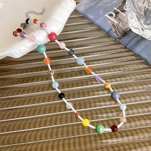 Detail of colorful beaded necklace with adjustable silver lobster clasp on textured surface