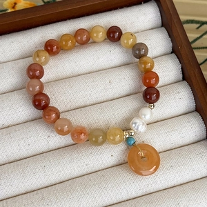 Vista macro del bracciale di perle multistrato con ciondolo di giada arancione
