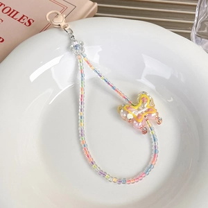 Détail d'une dragonne de téléphone perlée colorée avec papillon en résine et fermoir cœur