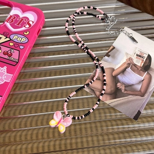 Detail of pink butterfly pendant and black beaded necklace with adjustable metal chain