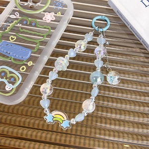 Détail de la dragonne de téléphone avec perles, cœur bleu et boule de verre pailletée