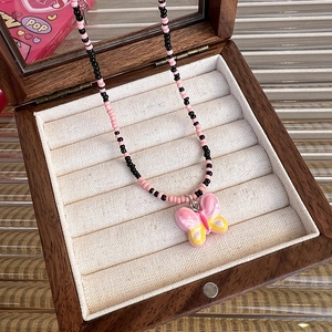 Close-up of pink and black beaded necklace with butterfly pendant in wooden jewelry box