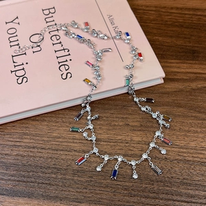 Détail du collier à pampilles en zircon coloré avec des gemmes sur fond de livre