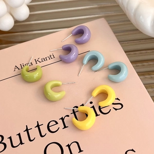 Macro view of macaron C-shaped stud earrings in pastel purple, blue, green, and yellow