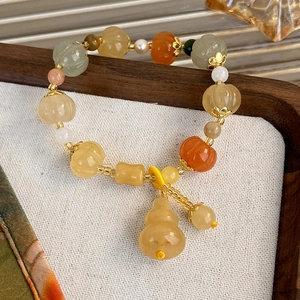 Detail view of pumpkin-shaped beads and a small gourd pendant on a Zen beaded bracelet
