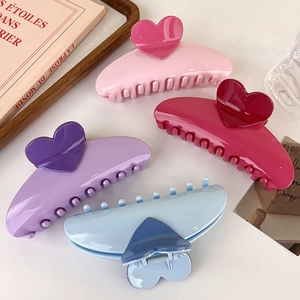 Lot de quatre pinces à cheveux en forme de cœur en tons rose, violet et bleu sur fond blanc