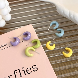 Detail of colorful C-shape candy earrings in purple, green, blue and yellow hues