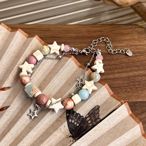 Detailed macro view of bohemian double-layer beaded bracelet with star charms on a folding fan