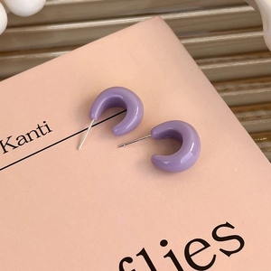 Close-up of purple C-shaped resin stud earrings on a minimalist decorative card