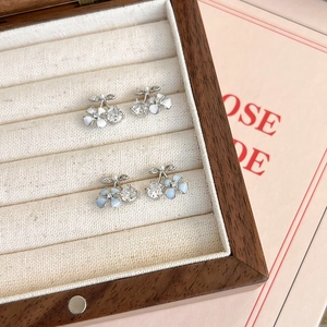 Boucles d'oreilles cerises avec zircons et pétales dans un écrin à bijoux en bois