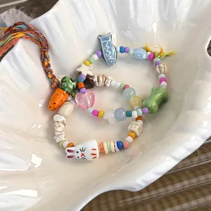 Detailed shot of handmade ceramic rabbit and carrot charms on colorful beaded bracelets