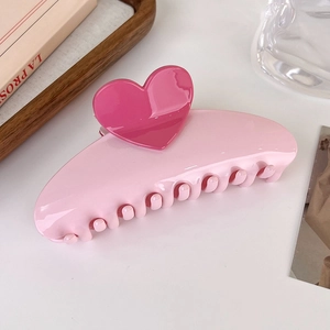 Vue détaillée d'une pince à cheveux rose en forme de cœur sur un bureau blanc chic