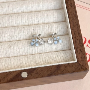 Gros plan de boucles d'oreilles cerisier avec pétales bleus et zircons en boîte