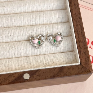 Détail de boucles d'oreilles cœur argenté avec tulipe rose, zircon et perle