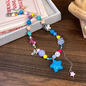 Détail d'un collier de perles colorées avec breloques étoile et cœur sur fond de bois