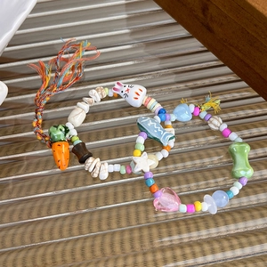 Macro detail of cute ceramic bunny and carrot charms on colorful beaded bracelets