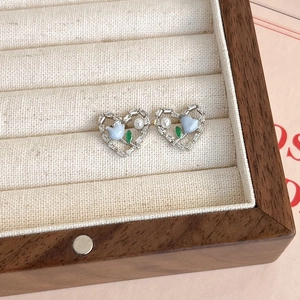 Détail d'une boucle d'oreille cœur argenté avec tulipe bleue, perle et zircone sur lin