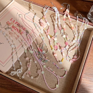 Gros plan de colliers de perles colorés avec breloques cœur, étoile et nœud au soleil