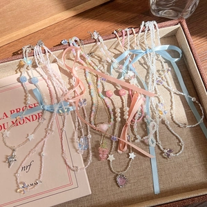 Détail de colliers de perles colorés avec breloques cœur, papillon et nœud aux tons macaron