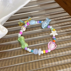 Detail of beaded bracelet with blue fish charm, heart beads and colorful tassel decor
