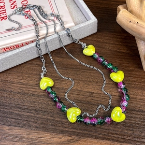 Gros plan d'un collier de perles colorées avec cœurs jaunes sur fond de bois vintage