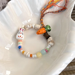Close-up of handmade rabbit and carrot ceramic bead bracelet with colorful woven tassel
