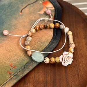 Detail of beaded bracelet set with rose charm, green jade stone and woven cord