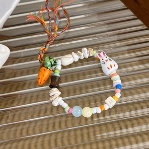 Detailed macro of ceramic bunny and carrot charms on a colorful handmade beaded bracelet