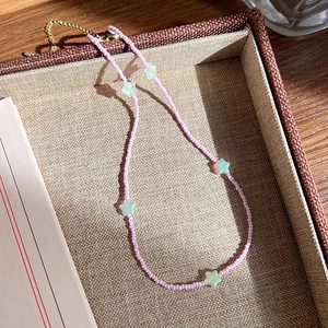 Vue détaillée du collier de perles roses avec étoiles sur un plateau marron