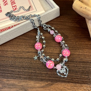 Détail d'un collier de perles à plusieurs rangs avec perles roses et pendentif cœur papillon