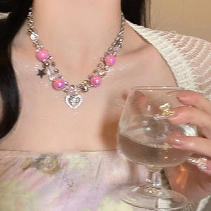 Détail du collier Y2K double couche avec perles métalliques et pendentifs cœur et étoile