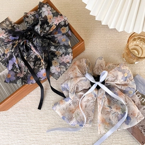 Détail de pinces à cheveux avec nœud en organza à fleurs et longs rubans décoratifs