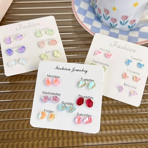 Macro shot of colorful resin butterfly and heart earring set on weekly fashion cards