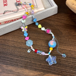 Détail de perles acryliques colorées, breloques cœur et étoile sur un collier ajustable