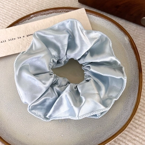 Eleganter cremeweißer Satin-Haargummi mit Seidentextur auf einer Vintage-Keramikschale