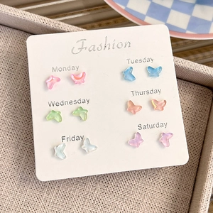 Macro view of colorful resin butterfly stud earrings set on a white fashion card display
