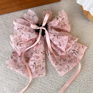 Détail d'une pince à cheveux avec nœud en mousseline rose et motif floral élégant