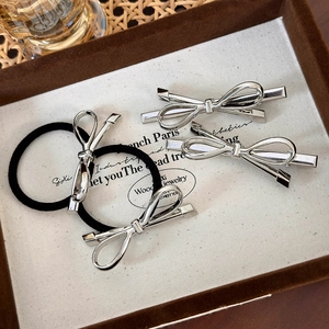 Set dettagliato di fermagli per capelli a fiocco argento e elastici su vassoio espositivo