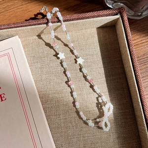 Détail du collier de perles fait main avec étoiles et pendentif nœud délicat
