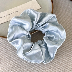 Nahaufnahme von hellblauem Satin-Haargummi mit eleganter zweilagiger Rüsche und Seidentextur