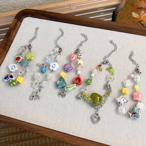 Cinq bracelets en perles de céramique colorées avec breloques cœur et papillon sur plateau
