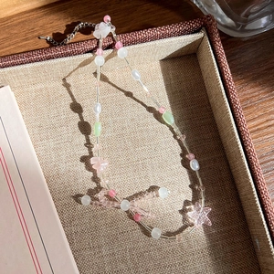 Gros plan d'un collier de perles roses avec pendentif étoile et détail de nœud élégant